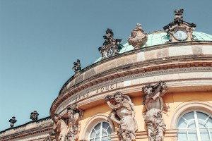 The historic Sanssouci Palace in Potsdam, known for its distinctive yellow facade and ornate atlantes.