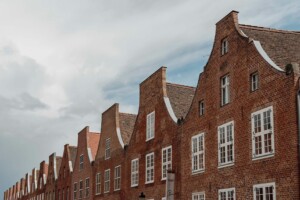 Row of historic brick houses with pointed gables in the Dutch Quarter under a cloudy sky.